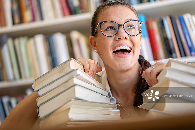 在图书馆的快乐美丽年轻女子-库存照片图片素材