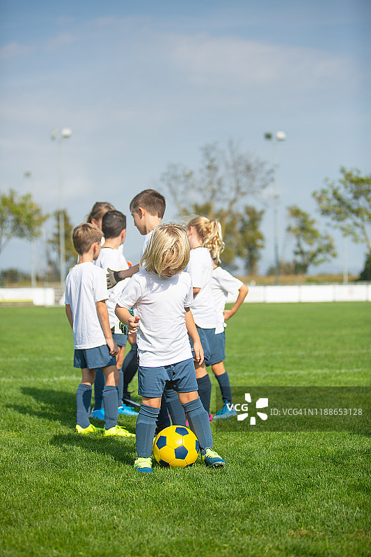 年轻的金发男子在足球场上练习控球图片素材