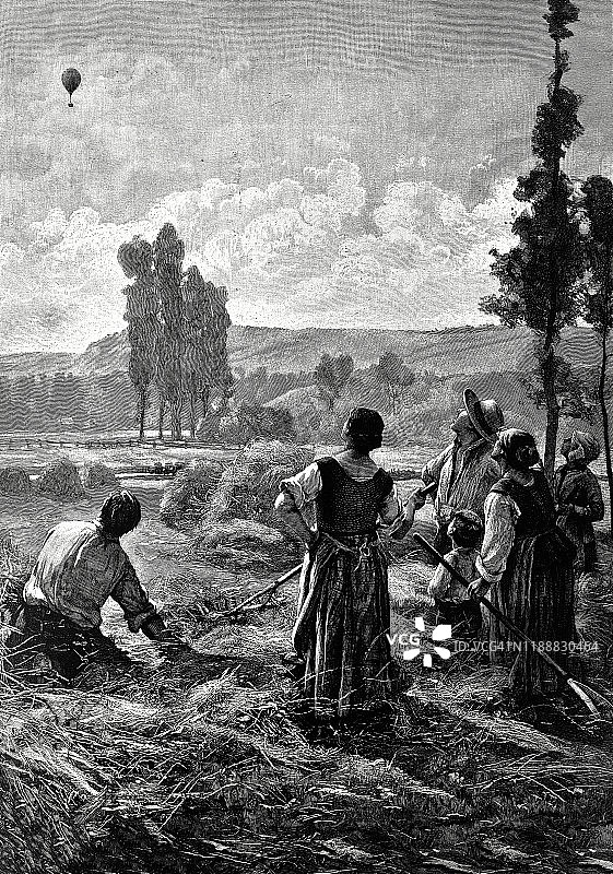 农民们注视着田野上空飞行的气球图片素材