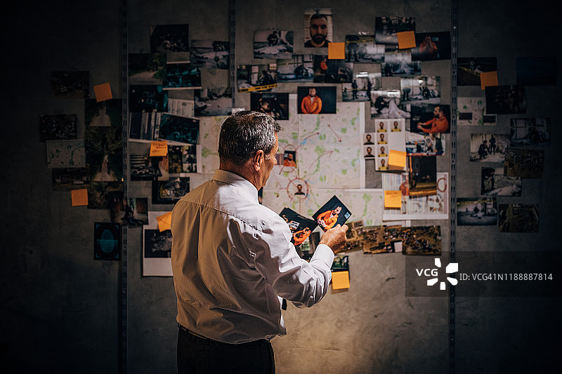 一位老侦探正在办公室里看嫌疑犯的照片图片素材