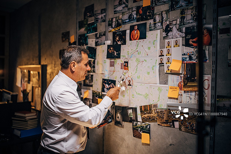 一位老侦探正在办公室里看嫌疑犯的照片图片素材