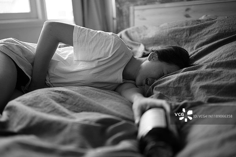 亚洲女性在床上感到经期疼痛图片素材