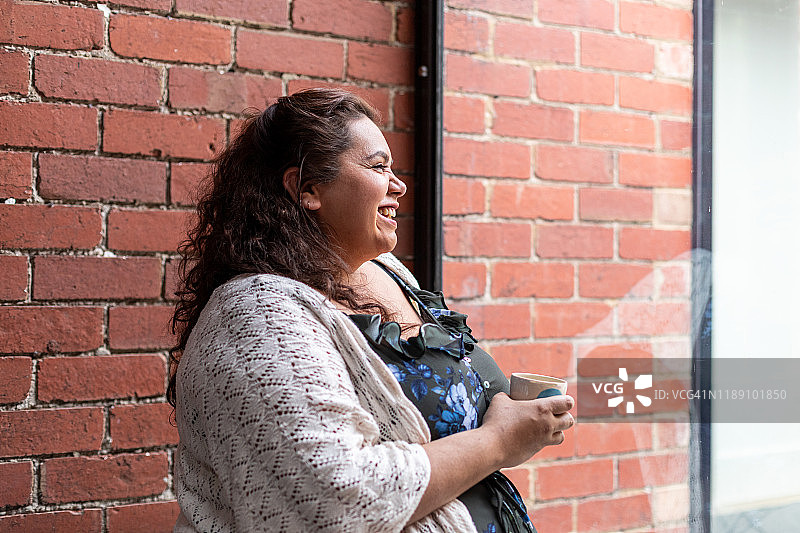 坐在窗边向外看并微笑的原住民妇女图片素材