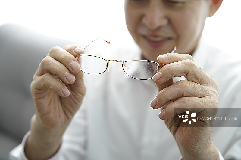 年长男性拿着眼镜的特写图片素材