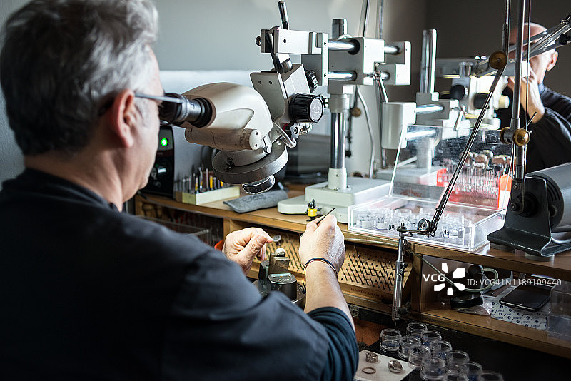 珠宝工艺实验室：使用显微镜的工人图片素材