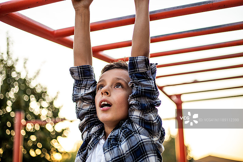 在操场上单杠上的健壮小男孩图片素材