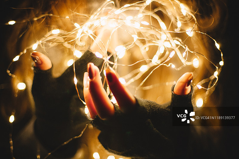 黑暗中女性手持圣诞灯特写图片素材