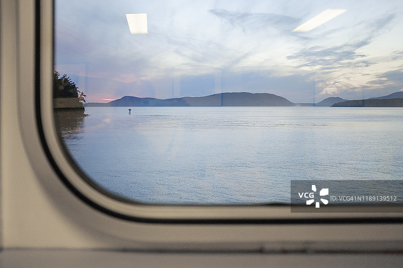 从渡轮的窗户眺望远处的日落岛屿图片素材