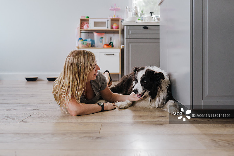 快乐的女人在家抚摸她的狗时微笑图片素材
