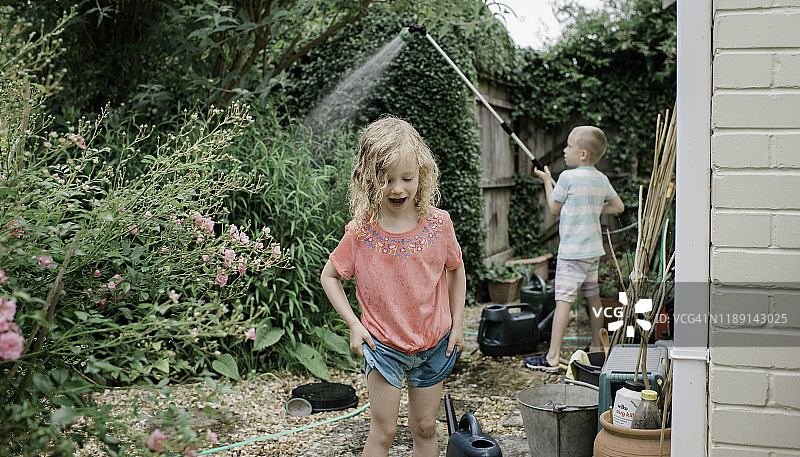 兄妹在英国乡村花园里玩水图片素材
