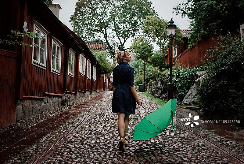 在鹅卵石街道上撑伞看雨的女人图片素材