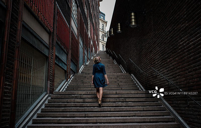 穿着连衣裙独自走在市中心台阶上的女人图片素材