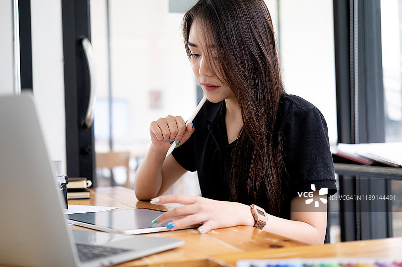 平面设计师在创意工作室办公室的办公桌前工作图片素材