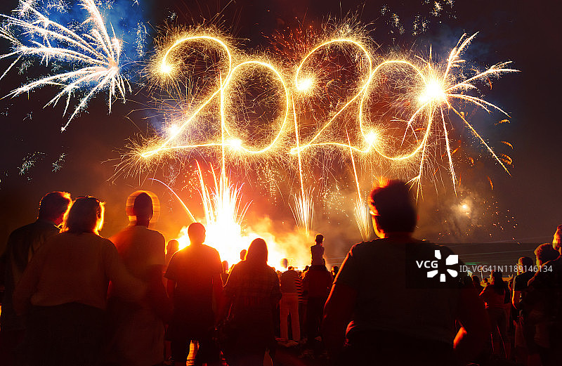 人群在充满活力的烟花前，手持烟花棒 - 2020字样图片素材