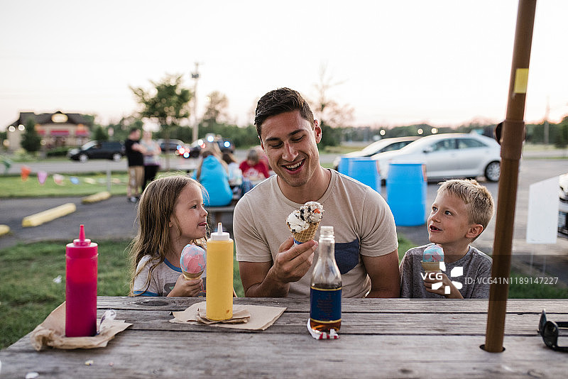 夏日夜晚在野餐桌旁吃冰淇淋的年轻人和儿童图片素材