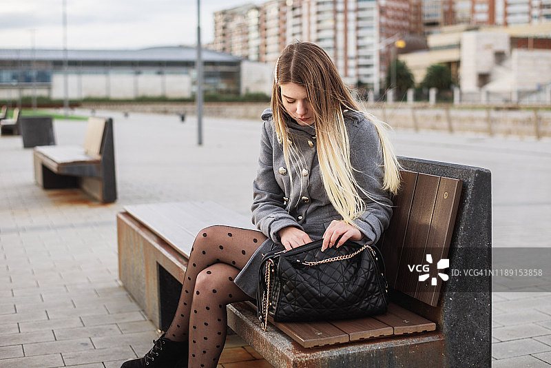 年轻女子在钱包里翻找图片素材