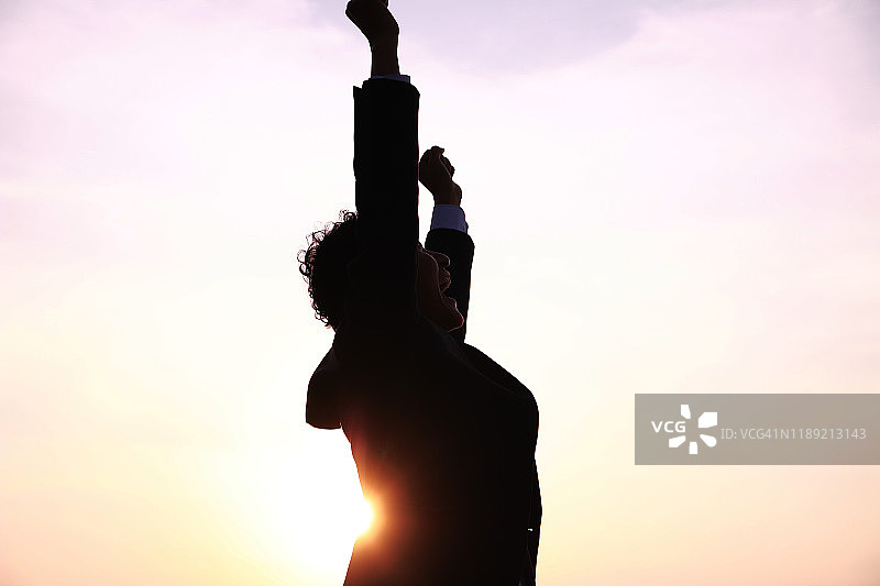 日落时分，商务人士张开双臂站立的剪影图片素材
