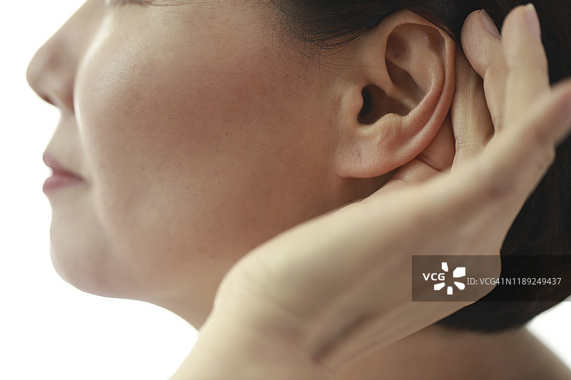用手放在耳边倾听的中年妇女图片素材