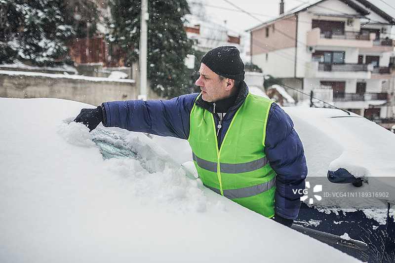 年长男人清理车上的雪图片素材