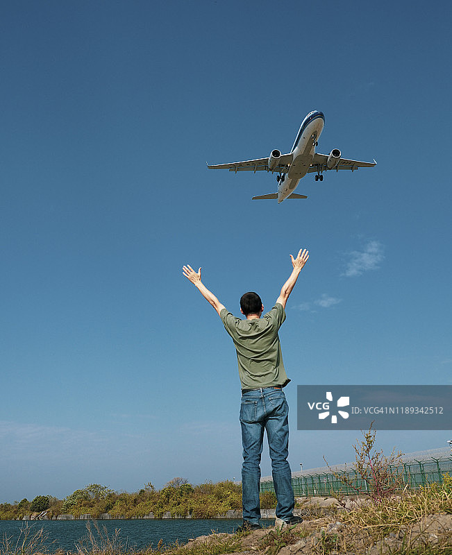 一位年轻男人在上海浦东机场观看飞机降落。图片素材
