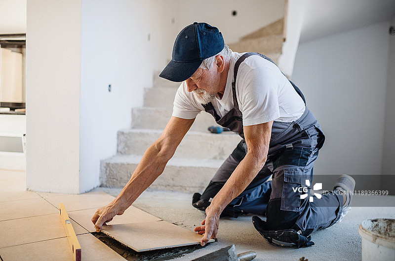 年长的男人在新家铺设瓷砖图片素材
