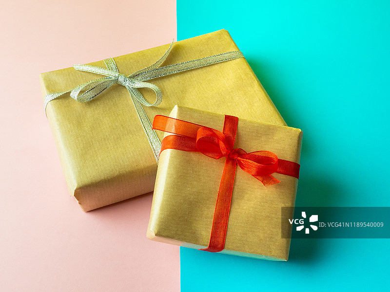 粉蓝背景上的棕色再生纸礼品包装，配红色和银色蝴蝶结图片素材