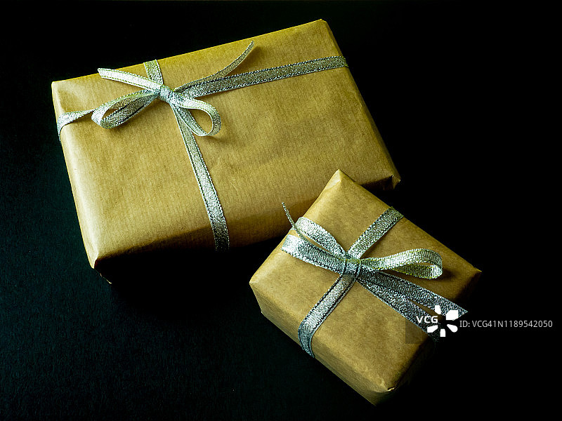 黑色背景上的棕色再生纸银色蝴蝶结礼品包装图片素材