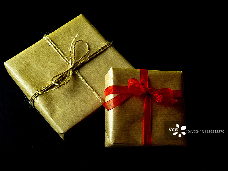 黑色背景上的棕色再生纸红色蝴蝶结礼品包装图片素材