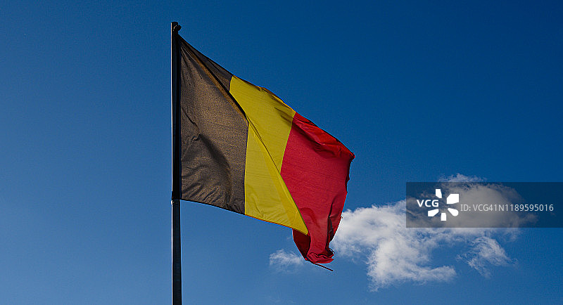 比利时迪南，蓝天白云下迎风飘扬的比利时国旗图片素材