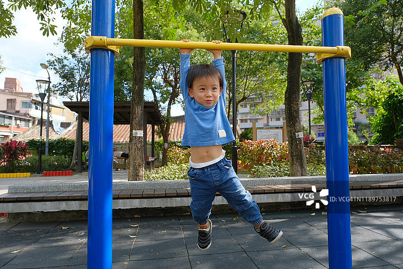 幼儿在游乐场单杠上锻炼图片素材
