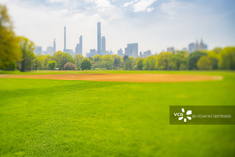纽约中央公园大草坪，摩天大楼掩映在绿树后图片素材