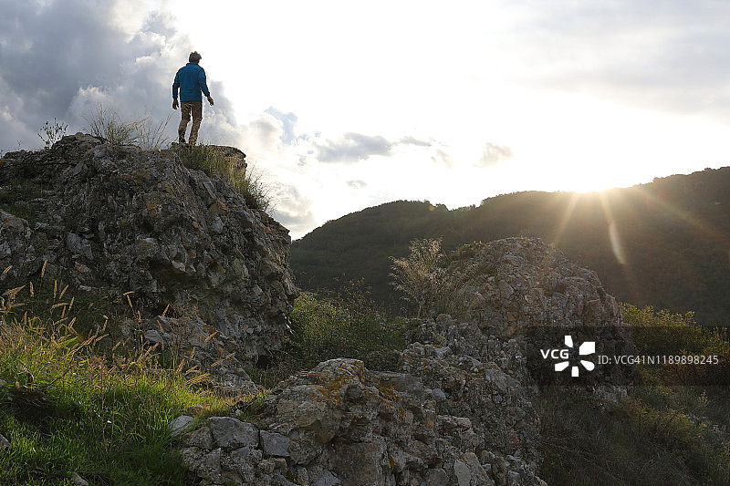 男人在日出时走到岩石瞭望台上图片素材