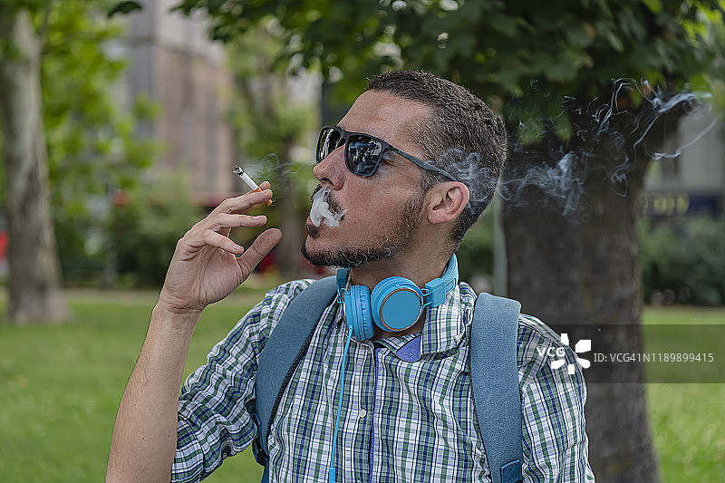 英俊的男人在户外吸烟图片素材