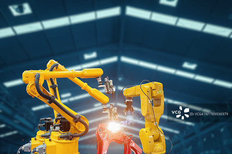 现代汽车零部件工厂中工作的自动焊接机器人机械臂图片素材