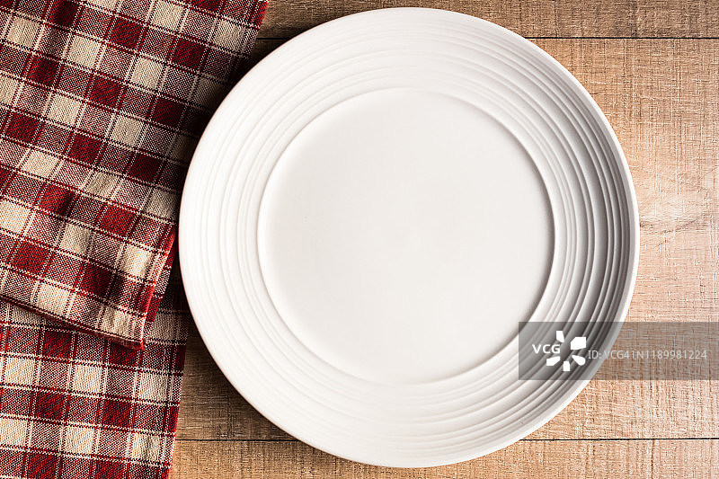 红色和白色格子餐巾上的白色空盘，俯视图图片素材