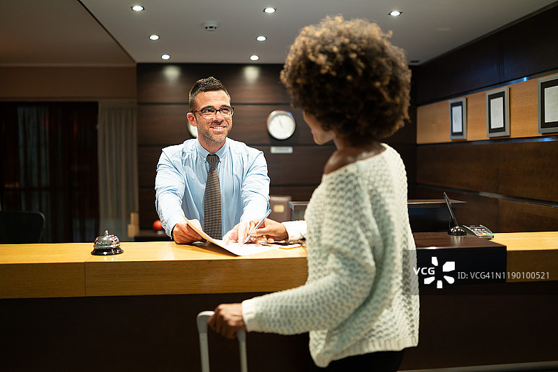 女人在前台办理酒店入住登记图片素材