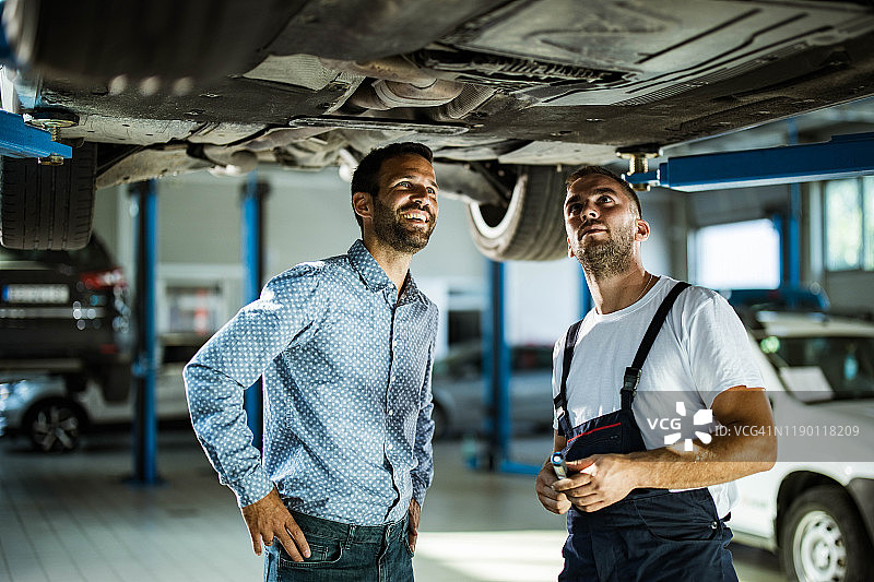 男经理和汽车修理工在车间检查汽车底盘图片素材