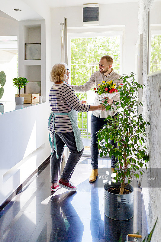 年长的妇女迎接年轻男子图片素材