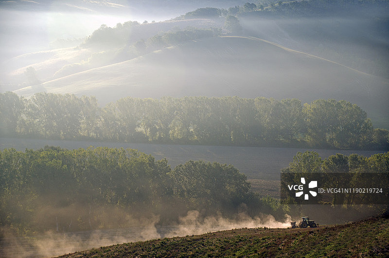 托斯卡纳早晨山丘上的农用拖拉机图片素材