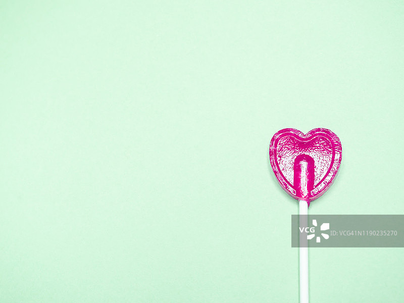 绿色背景中的粉色心形棒棒糖图片素材