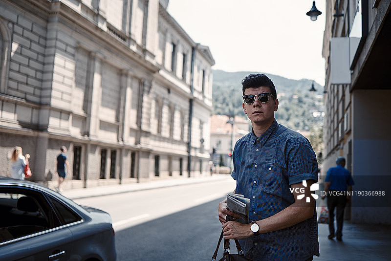 阳光明媚的一天，年轻的商务男士在街上拿着报纸图片素材