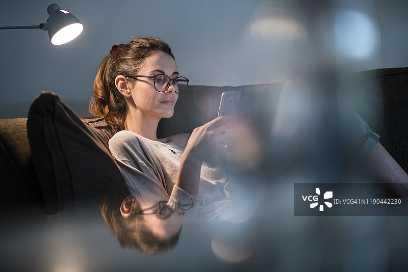 女子晚上在沙发上打电话图片素材