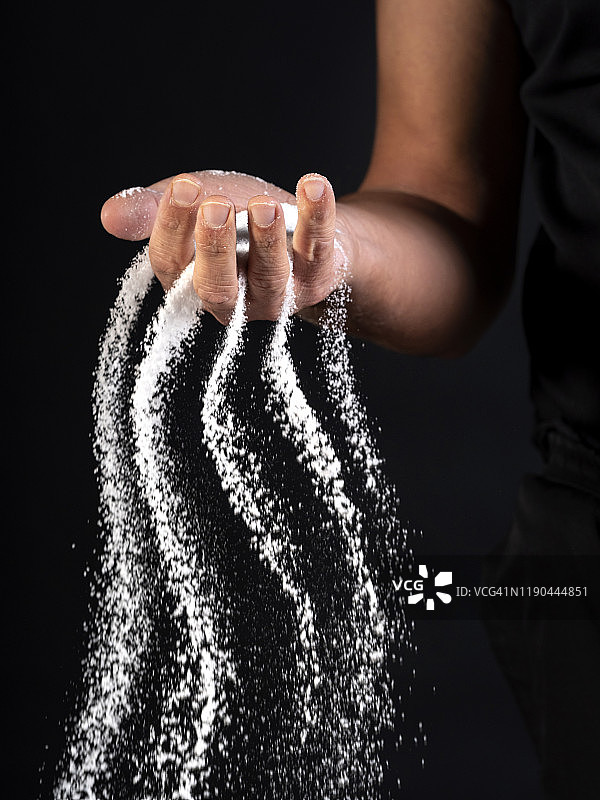 黑色背景上的手中的沙子图片素材