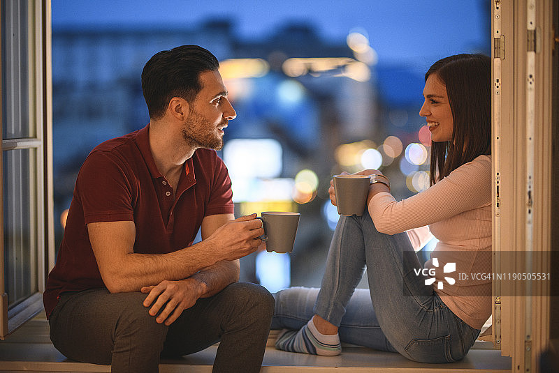 高加索夫妇在开放式窗户欣赏黄昏图片素材