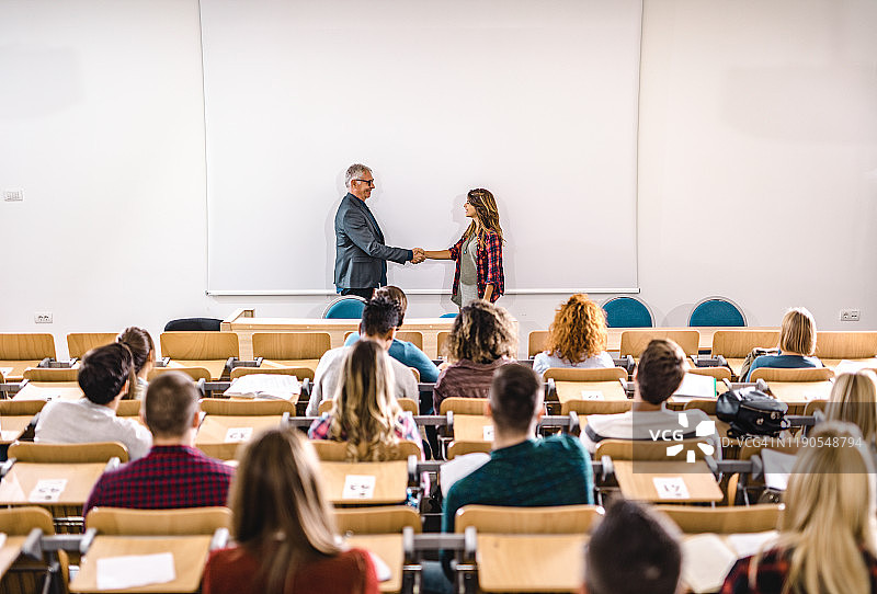 快乐的教授和大学生在白板前握手图片素材