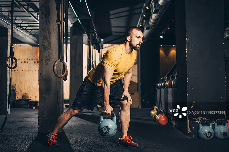 在健身房做壶铃弓步锻炼的健壮男人图片素材