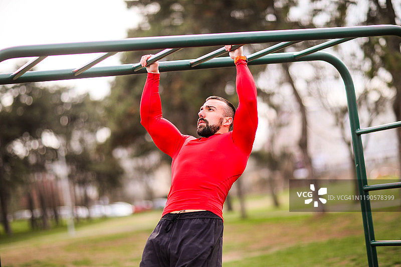 健壮的男人在城市公园的单杠上锻炼图片素材