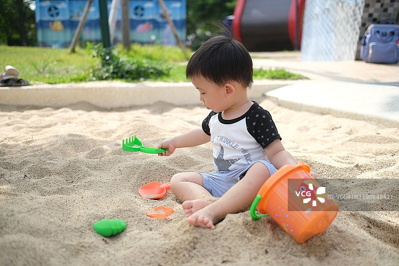 中国台湾幼儿男孩用铲子将沙子铲进桶里图片素材