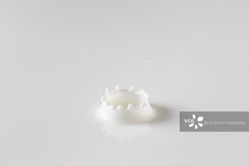 鲜牛奶滴入奶池，白色背景，带有圆形波纹图片素材