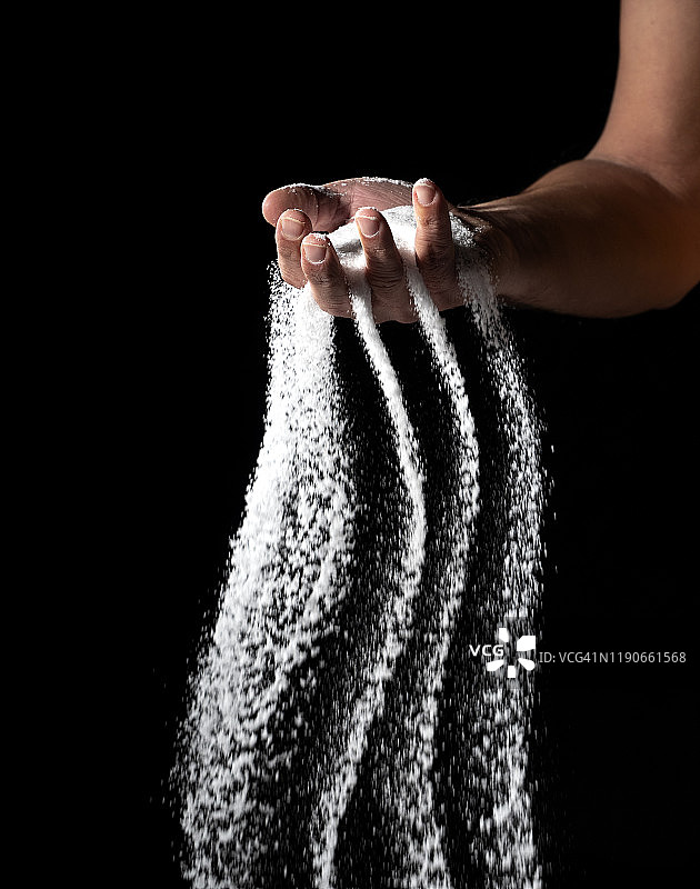 黑色背景上的手中的沙子图片素材